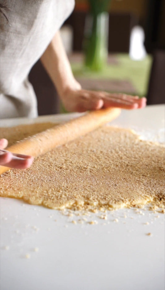Rolling out kiflyky dough with walnut filling — wearing a Polissia linen apron