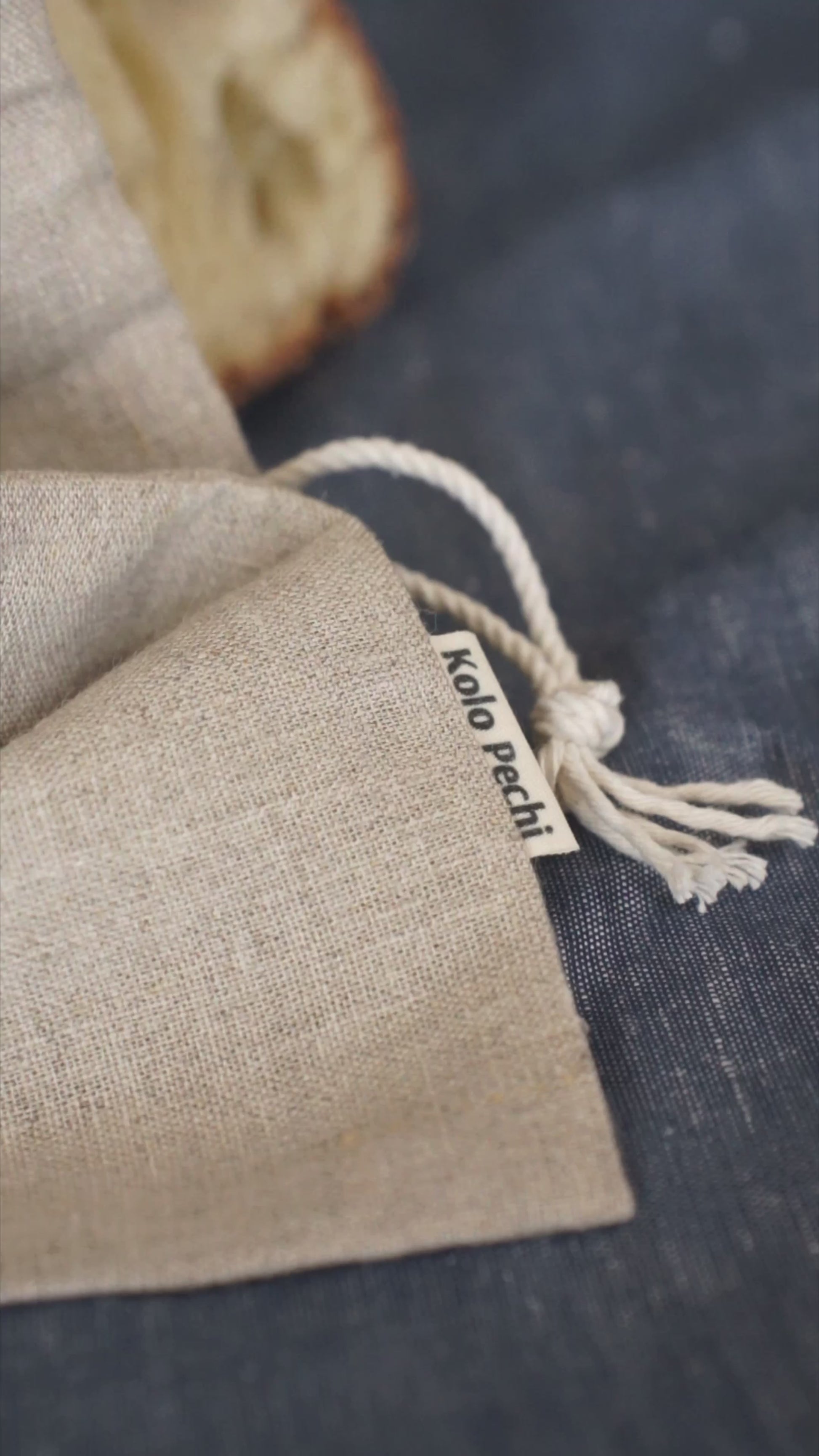 The Kolo Pechi linen bread bag with a loa of bread in it on the linen tea towel